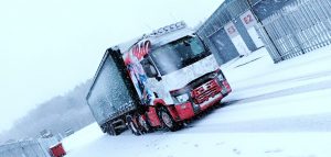 a white and red lorry driving through thick snow