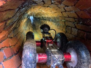 a remote controlled vehicle with a light attached going through a drain