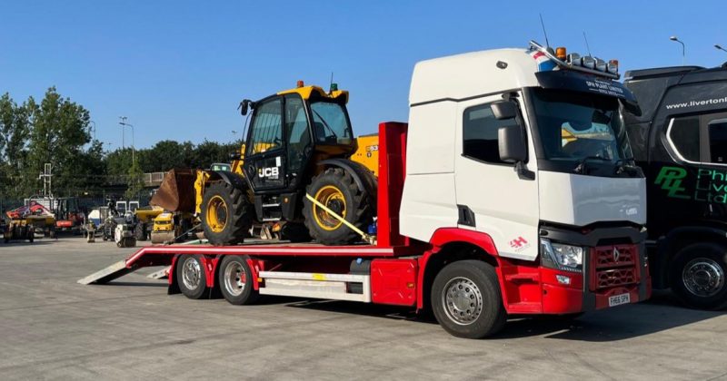 A truck carrying a JCB tractor