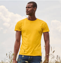 Man surrounded by long grass and beautiful blue and cloudy sky modelling a yellow T-shirt